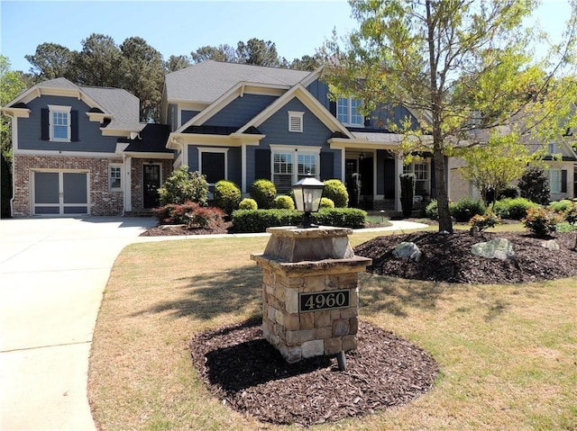 craftsman house featuring a front lawn, driveway, brick siding, and an attached garage