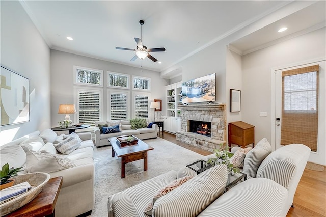 living room with a ceiling fan, crown molding, wood finished floors, recessed lighting, and a fireplace