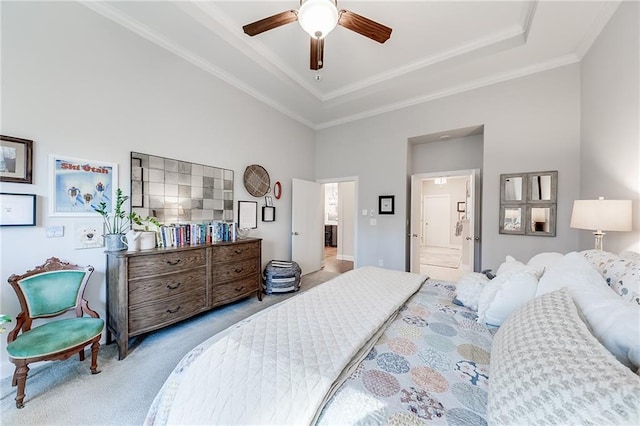 bedroom with carpet floors, a raised ceiling, crown molding, ensuite bath, and a ceiling fan