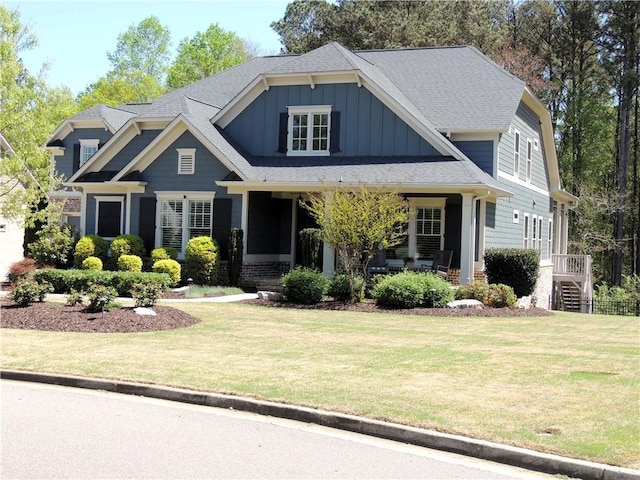 craftsman inspired home featuring board and batten siding, a front lawn, a shingled roof, and covered porch