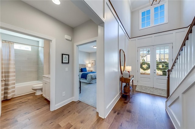 entrance foyer with wood finished floors, healthy amount of natural light, french doors, and stairs
