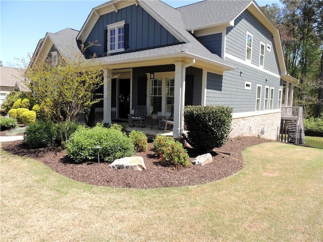 craftsman inspired home featuring a front yard, board and batten siding, roof with shingles, and covered porch