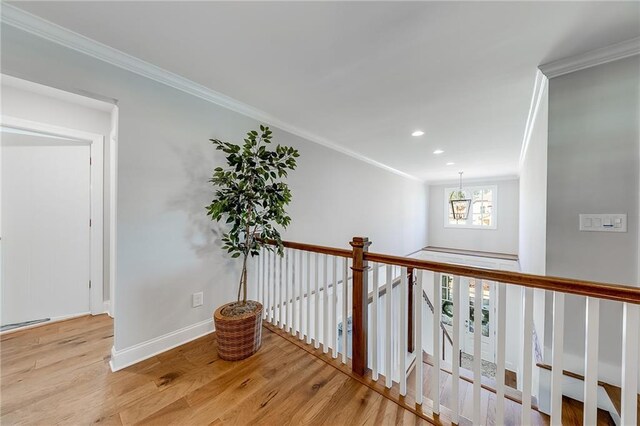 hallway featuring wood finished floors, crown molding, a chandelier, baseboards, and an upstairs landing