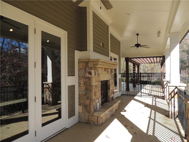 view of patio featuring a ceiling fan, an outdoor stone fireplace, and french doors
