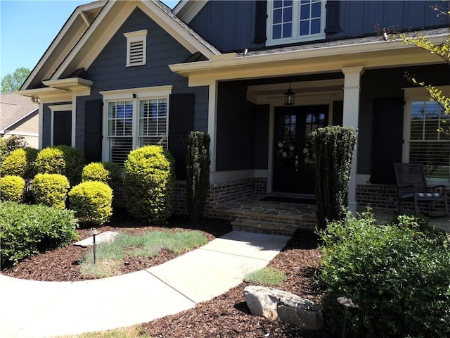 view of exterior entry featuring board and batten siding, covered porch, and french doors