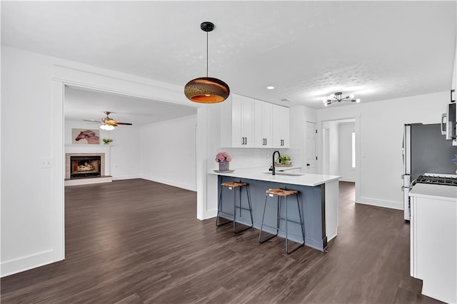 kitchen with a sink, white cabinets, baseboards, dark wood-style floors, and a breakfast bar