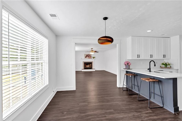 corridor featuring a sink, dark wood finished floors, baseboards, and recessed lighting