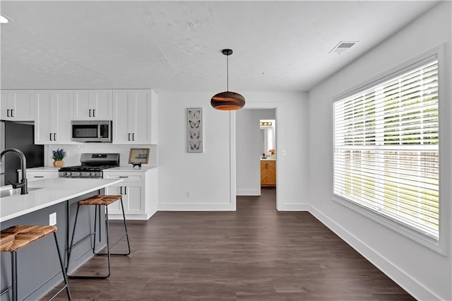 kitchen featuring appliances with stainless steel finishes, baseboards, white cabinets, and light countertops