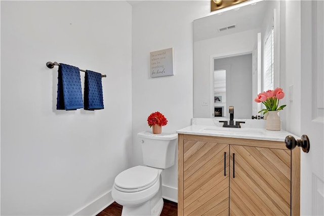 bathroom with toilet, baseboards, vanity, and wood finished floors