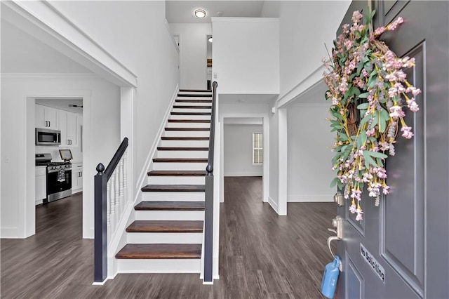 foyer with stairs, dark wood-style flooring, baseboards, a towering ceiling, and crown molding