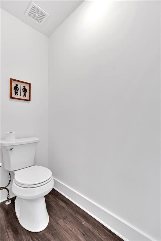 bathroom with wood finished floors, toilet, and baseboards