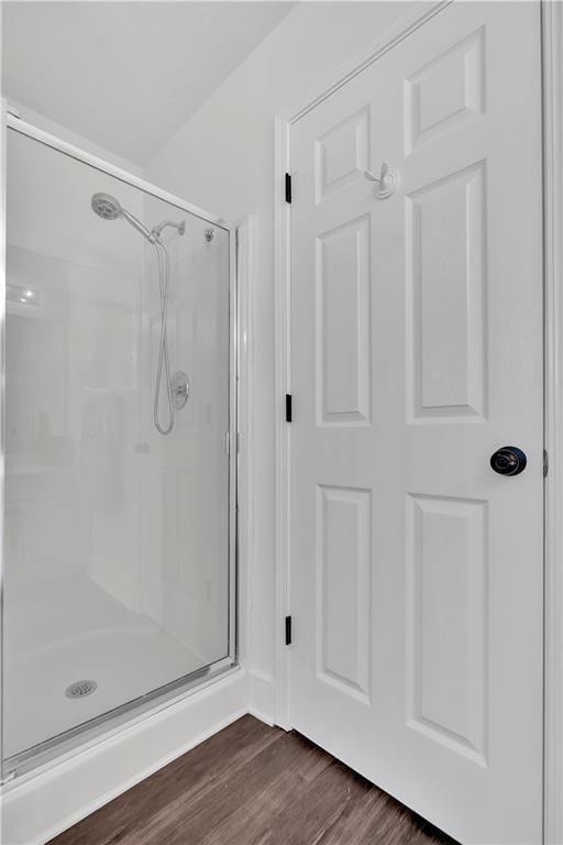 full bath featuring a stall shower and wood finished floors