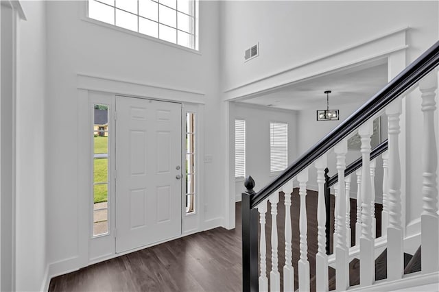 entryway featuring healthy amount of natural light, dark wood-style floors, stairway, baseboards, and a high ceiling