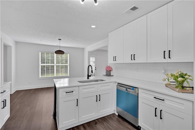 kitchen with dishwashing machine, a sink, a peninsula, light countertops, and tasteful backsplash