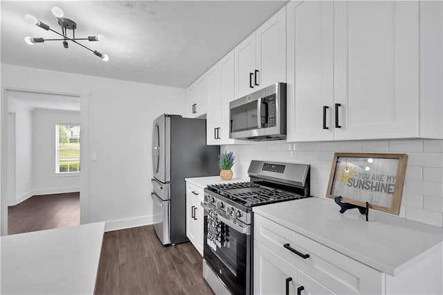 kitchen featuring stainless steel appliances, dark wood finished floors, decorative backsplash, baseboards, and light countertops