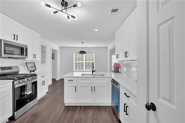 kitchen featuring stainless steel appliances, a sink, a peninsula, light countertops, and white cabinetry
