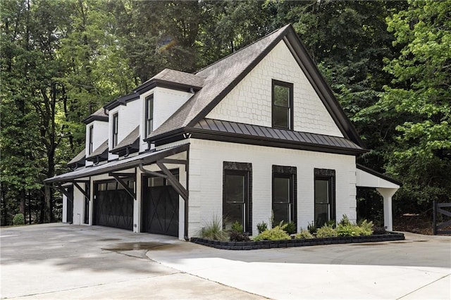 1217 Cabin Bridge Rd, Bethlehem, GA 30620 - view of front of house featuring a standing seam roof, concrete driveway, brick siding, a garage, and view of scattered trees