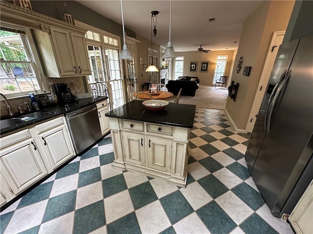 3962 Fox Glen Dr, Woodstock, GA 30189 - kitchen with appliances with stainless steel finishes, cream cabinets, dark countertops, dark flooring, and open floor plan