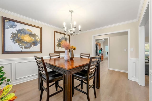 dining room with ornamental molding, light wood-type flooring, and a notable chandelier