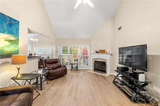 living room featuring ceiling fan with notable chandelier, high vaulted ceiling, and light hardwood / wood-style flooring