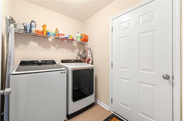 clothes washing area with light hardwood / wood-style floors and washing machine and clothes dryer