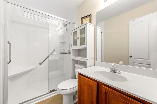 bathroom with hardwood / wood-style flooring, vanity, a shower with shower door, and toilet