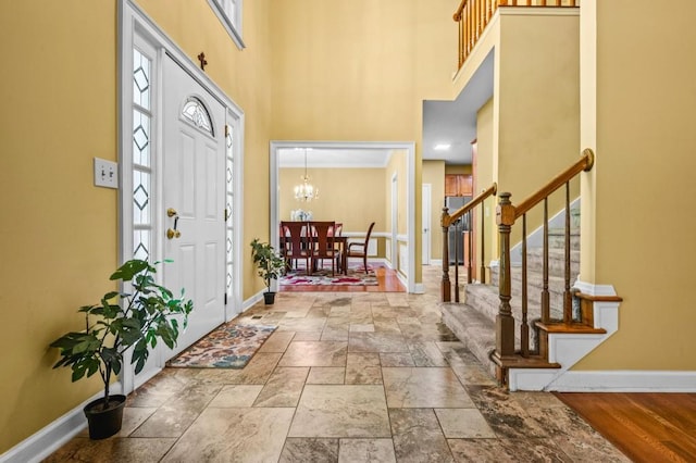 2610 Chadwick Rd, Marietta, GA 30066 - foyer featuring baseboards, stairway, a towering ceiling, stone finish floors, and a chandelier