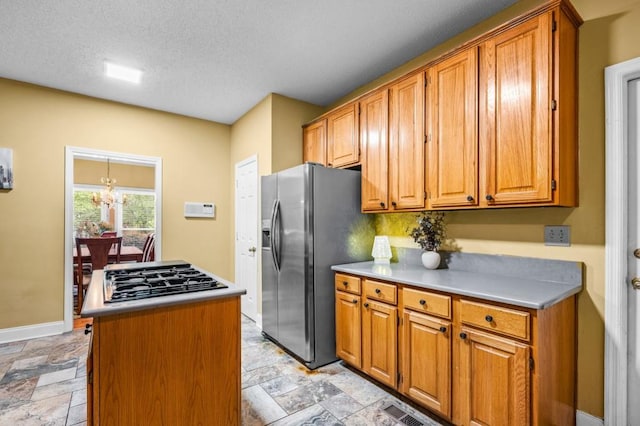 2610 Chadwick Rd, Marietta, GA 30066 - kitchen with black gas stovetop, stainless steel refrigerator with ice dispenser, stone tile floors, brown cabinetry, and a textured ceiling