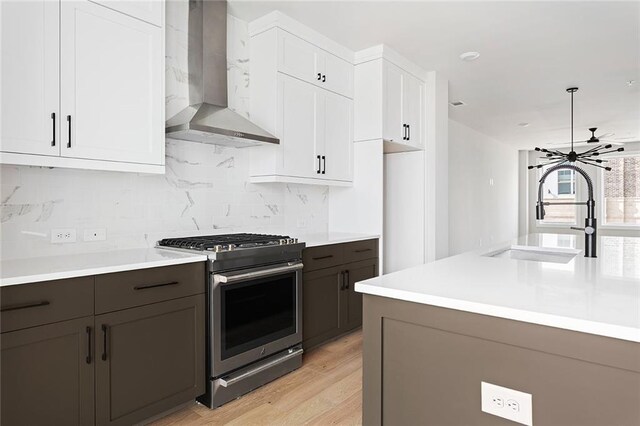 7210 Summit Pl, Alpharetta, GA 30009 - kitchen with stainless steel gas stove, wall chimney exhaust hood, a sink, white cabinetry, and light countertops