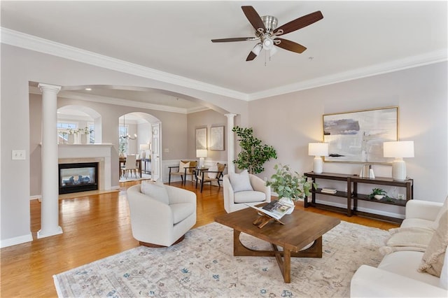 living room with crown molding, ceiling fan, light hardwood / wood-style floors, and ornate columns