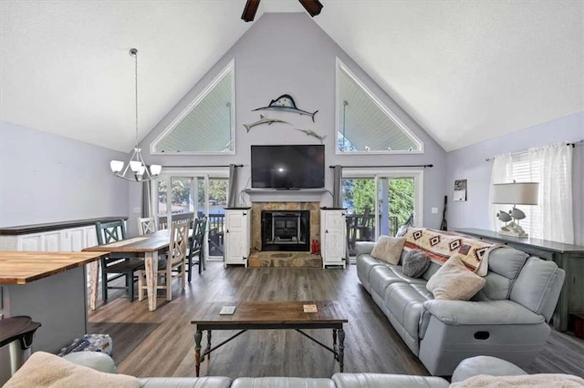 living room featuring a healthy amount of sunlight, high vaulted ceiling, a fireplace, and dark hardwood / wood-style flooring