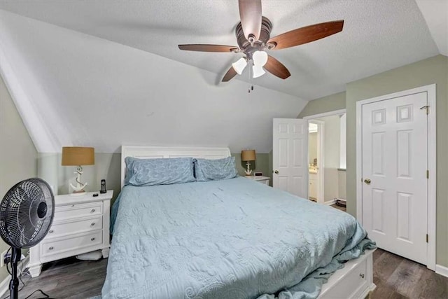 bedroom featuring dark wood-type flooring, ceiling fan, a textured ceiling, and vaulted ceiling