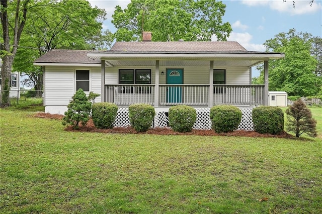 view of front of home with a porch, fence, a front lawn, and a chimney