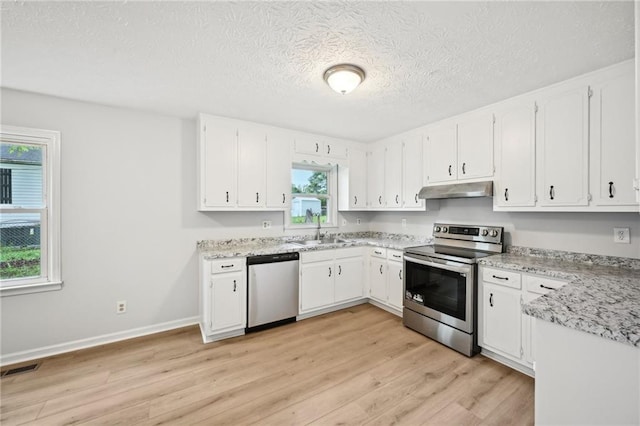 kitchen featuring appliances with stainless steel finishes, under cabinet range hood, a sink, white cabinetry, and light wood-type flooring