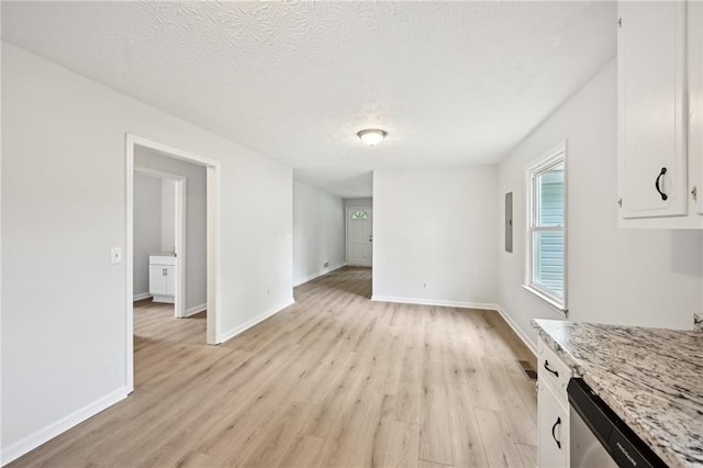 unfurnished dining area featuring baseboards, light wood finished floors, and a textured ceiling