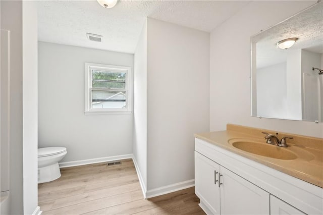 bathroom featuring vanity, a textured ceiling, visible vents, and wood finished floors
