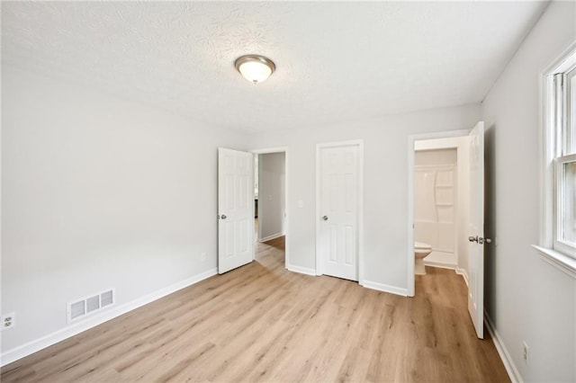 unfurnished bedroom with baseboards, visible vents, and wood finished floors