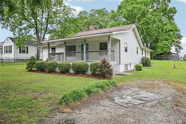 view of front of home featuring a chimney, a front lawn, covered porch, and fence
