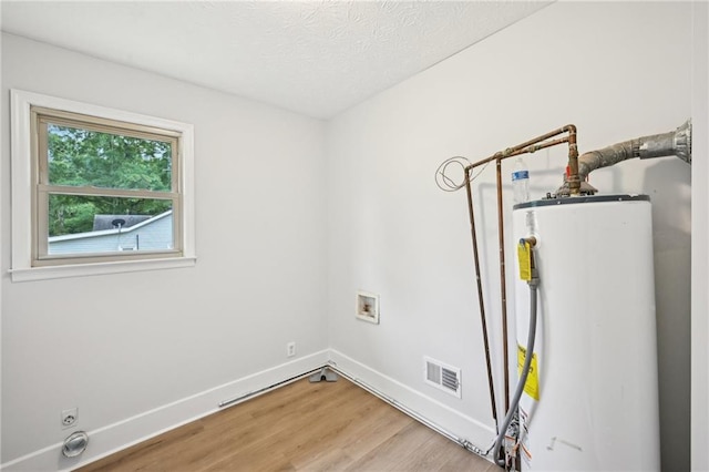 laundry area with hookup for a washing machine, visible vents, laundry area, light wood-type flooring, and water heater
