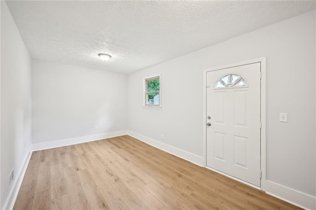 foyer featuring light wood-type flooring, visible vents, baseboards, and a textured ceiling