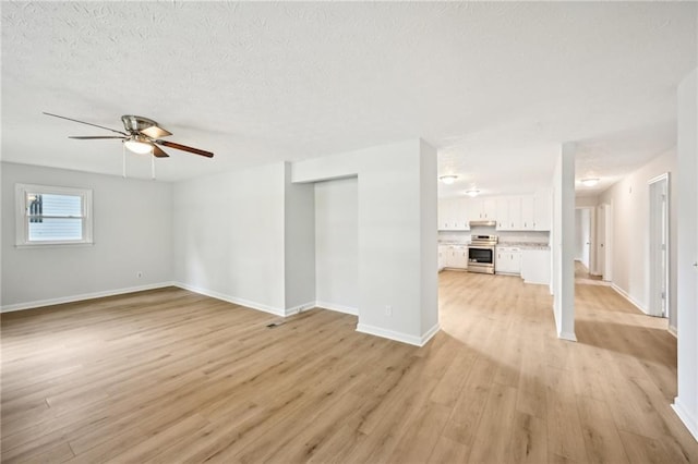 unfurnished living room with light wood-style flooring, a textured ceiling, baseboards, and a ceiling fan