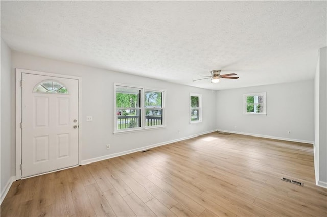 foyer entrance with ceiling fan, a textured ceiling, and baseboards