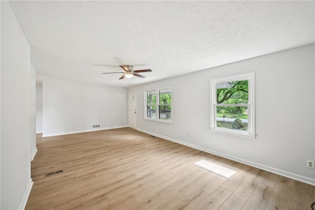 empty room featuring a ceiling fan, baseboards, light wood-type flooring, and visible vents