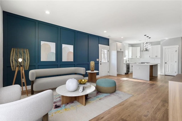 living area featuring recessed lighting, light wood-style flooring, and a decorative wall