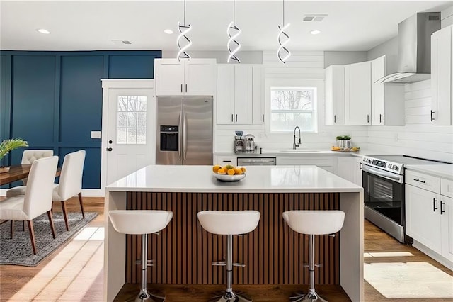 kitchen with stainless steel appliances, a center island, light countertops, and hanging light fixtures