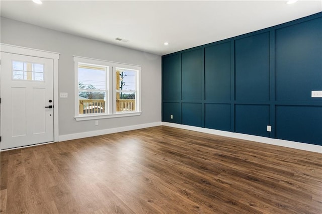 entryway featuring visible vents, baseboards, wood finished floors, a decorative wall, and recessed lighting