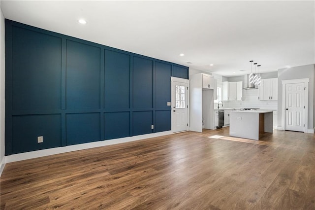 unfurnished living room with recessed lighting, wood finished floors, and a decorative wall