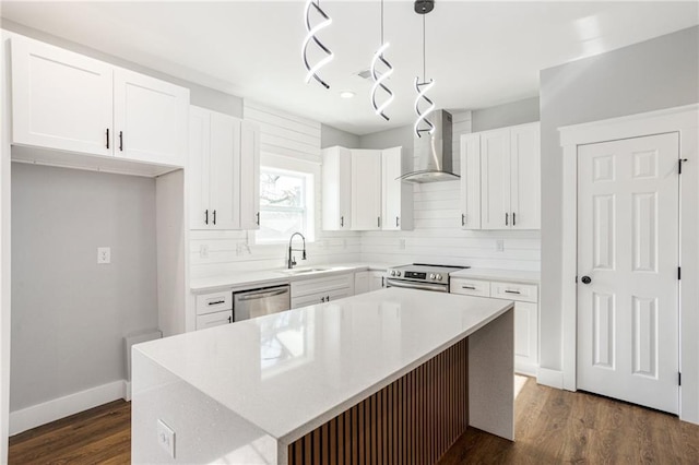 kitchen featuring a kitchen island, sink, hanging light fixtures, stainless steel appliances, and wall chimney exhaust hood