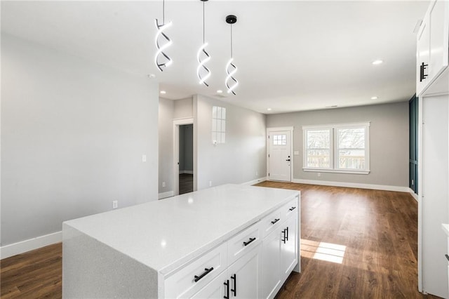 kitchen with white cabinetry, dark hardwood / wood-style flooring, a center island, and pendant lighting