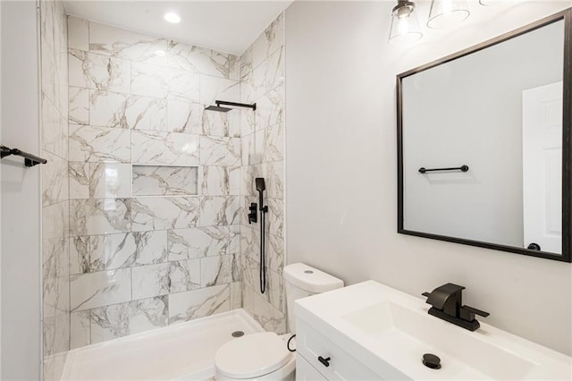 bathroom with vanity, a tile shower, and toilet